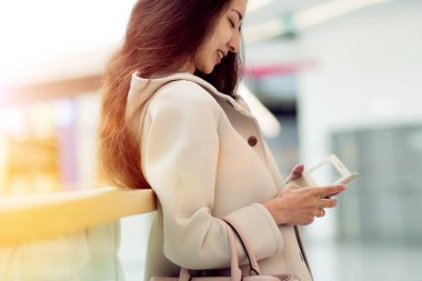 Genç kadın bej bir palto kullanır sosyal ağ uygulaması, yaşam tarzı. Çok etnik gruptan oluşan kız