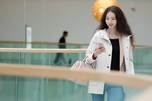 年轻漂亮的女孩亚洲，使用移动电话、 背景、 购物中心或商务中心 — 图库照片