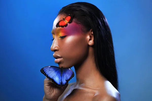 Joven chica afro hermosa, con dos mariposas, retrato de belleza sobre fondo azul — Foto de Stock