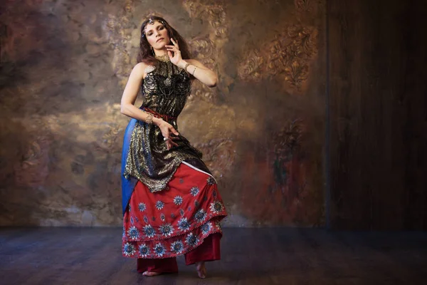 Güzel kadın Hint kostümü dokulu bir arka plan üzerinde dans.