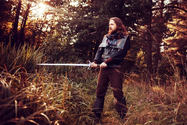 Chevalier dans la forêt. Un type en costume médiéval avec une épée — Photo