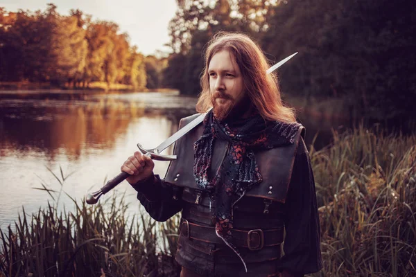 Cavaleiro na floresta. Um tipo de fato medieval com uma espada — Fotografia de Stock