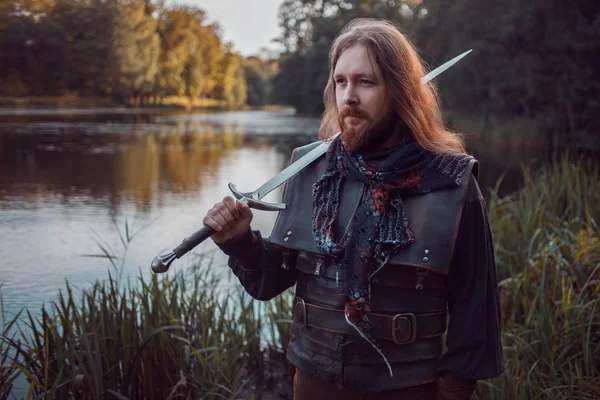 Knight in the forest. A guy in medieval costume with a sword — Stock Photo, Image