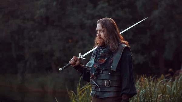 Knight in the forest. A guy in medieval costume with a sword — Stock Photo, Image