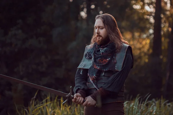 Cavaleiro na floresta. Um tipo de fato medieval com uma espada — Fotografia de Stock