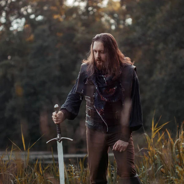 Cavaleiro na floresta. Um tipo de fato medieval com uma espada — Fotografia de Stock