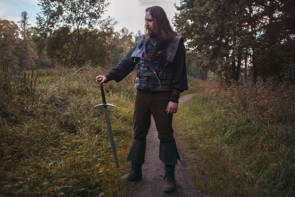 Knight in the forest. A guy in medieval costume with a sword — Stock Photo, Image