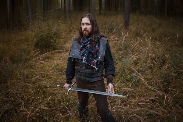 Knight in the forest. A guy in medieval costume with a sword — Stock Photo, Image