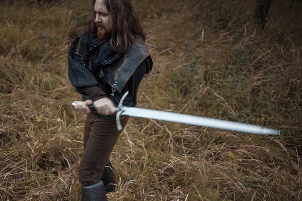 Battle. Knight in the forest. A guy in medieval costume with a sword — Stock Photo, Image