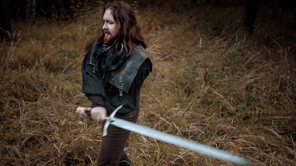 Batalla. Caballero en el bosque. Un tipo en traje medieval con una espada —  Fotos de Stock