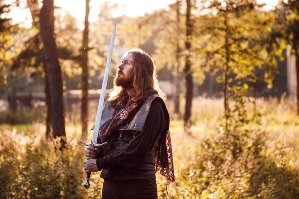 Cavaleiro na floresta. Um tipo de fato medieval com uma espada — Fotografia de Stock