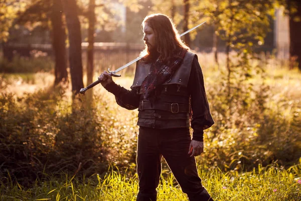 Knight in the forest. A guy in medieval costume with a sword — Stock Photo, Image