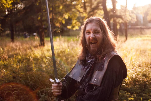 Battle. Knight in the forest. A guy in medieval costume with a sword — Stock Photo, Image