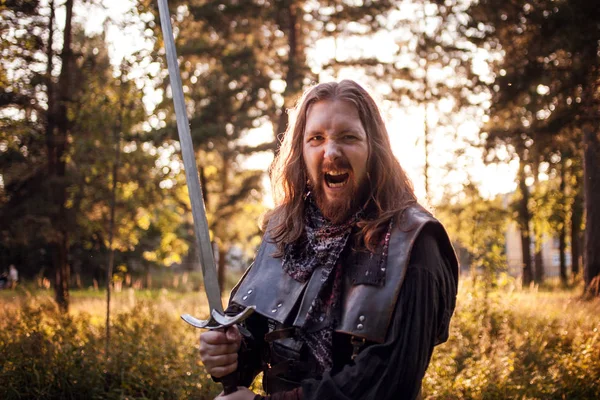 Battle. Knight in the forest. A guy in medieval costume with a sword — Stock Photo, Image