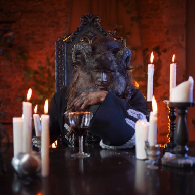 Adam canavar masada oturan bir cam ile el boynuzları ile görüntü.