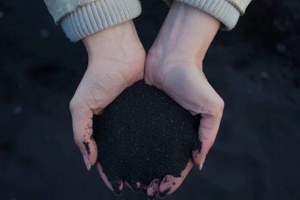 Černý vulkanický písek v rukou cestovatel. Island, pláž Vik. pohled z vrcholu — Stock fotografie