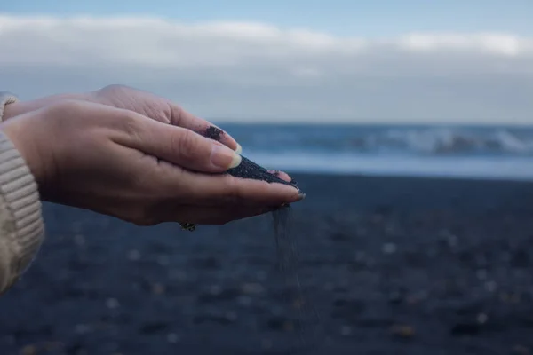 Black volcanic sand in the hands of the traveler. Iceland, beach of Vik — Stock Photo, Image