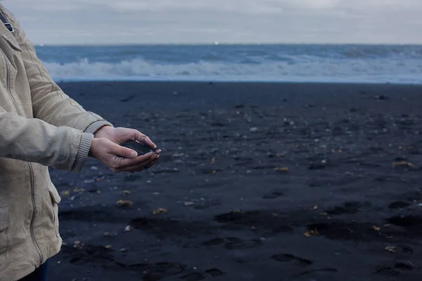 Black volcanic sand in the hands of the traveler. Iceland, beach of Vik — Stock Photo, Image