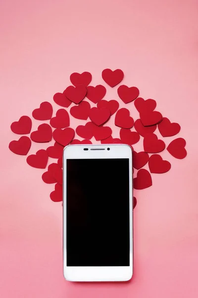 Vele harten en smartphone. Het concept graag in sociale netwerken of Dating app. roze achtergrond — Stockfoto
