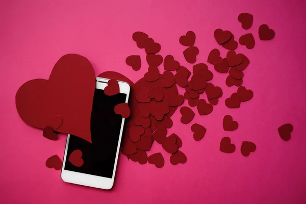 Багато сердець і смартфона. Концепція подобається в соціальних мережах або додатку знайомств. рожевий фон — стокове фото