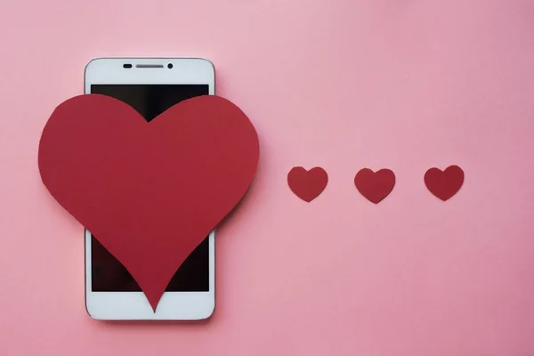 Валентин и смартфон. Идея понравиться в социальных сетях или приложении для знакомств. розовый фон — стоковое фото