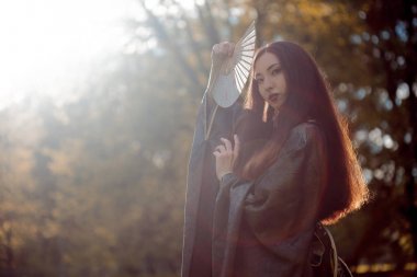 Genç güzel Asyalılar gri kimono ve açık bir fan ile portresi