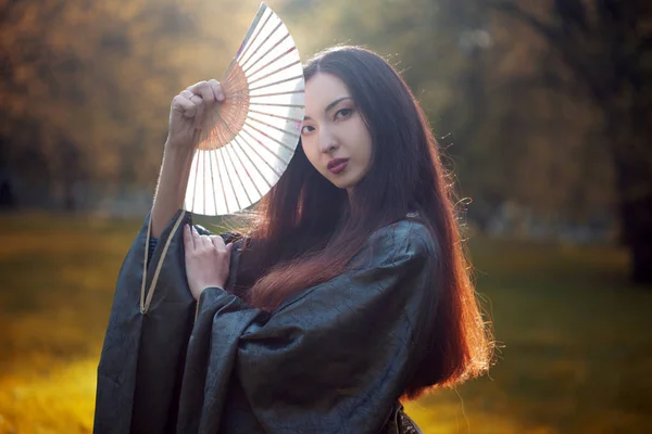 Genç güzel Asyalılar gri kimono ve bir fan ile portresi — Stok fotoğraf