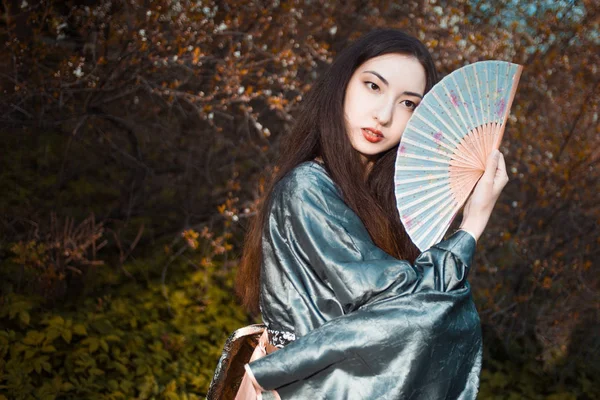 Retrato de jóvenes bellos asiáticos en kimono gris y con abanico — Foto de Stock