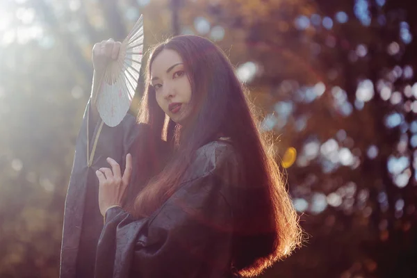 Ritratto di giovani belle asiatiche in kimono grigio e con ventilatore, esterno — Foto Stock