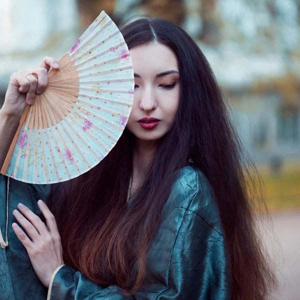 Porträtt av unga vackra asiater i grå kimono och fläkt — Stockfoto