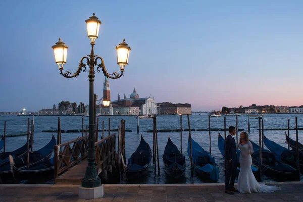 VENICE, ITALY - 7 октября 2017 года: невеста и жених на площади Сан-Марко, гондолы на заднем плане — стоковое фото