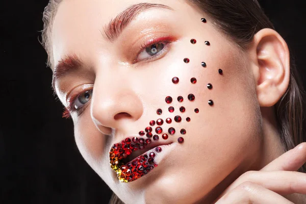 Joven chica hermosa con ojos azules. Maquillaje brillante, lápiz labial rojo. Arte, pedrería en los labios y la cara —  Fotos de Stock