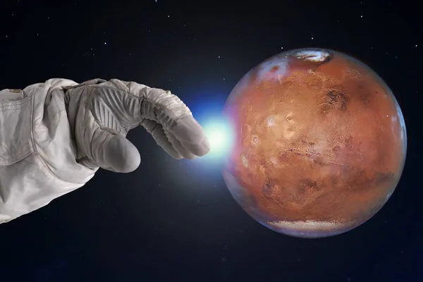 Le développement de Mars, concept. La main de l'astronaute tend la main vers Mars. Éléments de cette image fournis par la NASA . — Photo