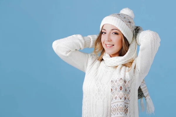 Fiatal és vonzó nő, kötött pulóver, sál, kalap, kék háttér — Stock Fotó