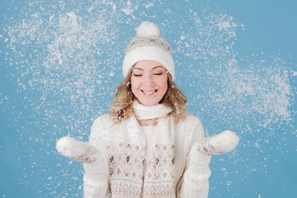 Νέοι και ελκυστική γυναίκα σε ένα πλεκτό πουλόβερ, παίζει με το χιόνι. μπλε φόντο — Φωτογραφία Αρχείου