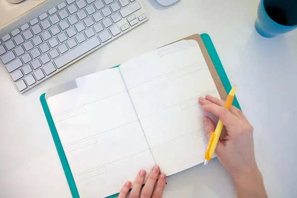 Young businesswoman sitting at desk and working. Beautiful woman fills planner, view from the top — Stock Photo, Image