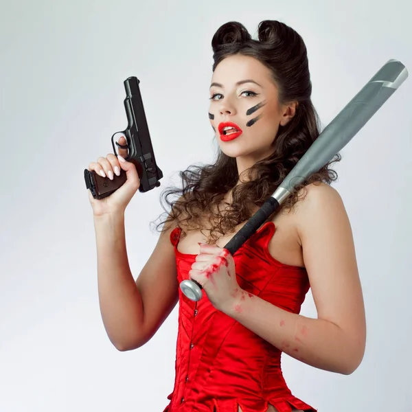 Женщина в красном с пистолетом и летучая мышь в боевой краске, женская сила — стоковое фото