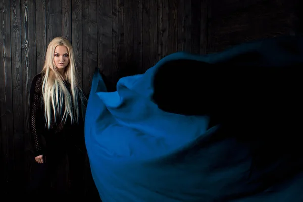 Elegante rubia sobre un fondo oscuro con tela voladora brillante, color azul —  Fotos de Stock