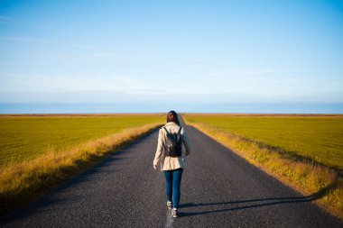 Kadın turist arka plan yolda sırt çantası ile. Hedefe doğru