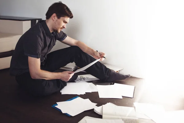 Young male entrepreneur makes brainstorming sitting on the floor in the apartment. Creative approach to business — Stock Photo, Image