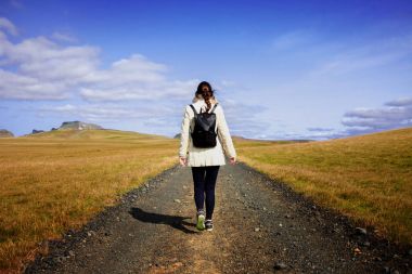 Kadın turist arka plan yolda sırt çantası ile. Hedefe doğru