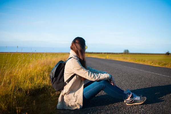 Young woman tourist sits on the road. — Stock Photo, Image