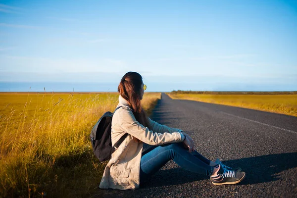 Young woman tourist sits on the road. — Stock Photo, Image