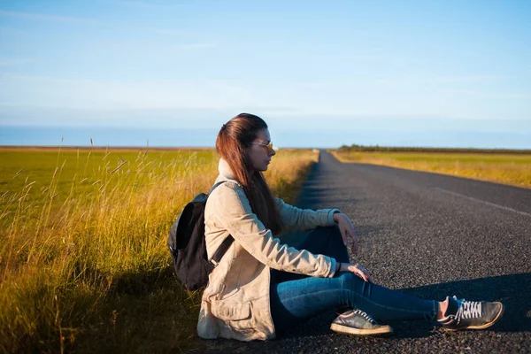 Young woman tourist sits on the road. — Stock Photo, Image