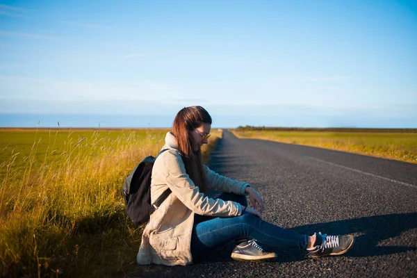 Young woman tourist sits on the road. — Stock Photo, Image