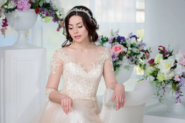 Porträt eines schönen Mädchens in einem luxuriösen Hochzeitskleid. Interieur mit Blumen dekoriert — Stockfoto
