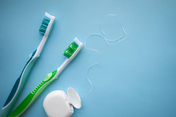 Two toothbrushes and dental floss on blue background — Stock Photo, Image