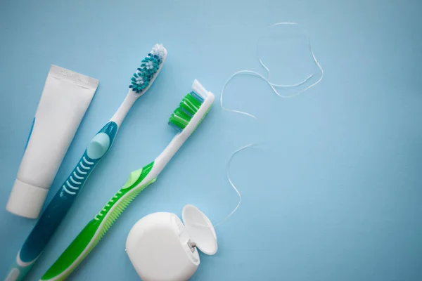 Dos cepillos de dientes y hilo dental sobre fondo azul —  Fotos de Stock