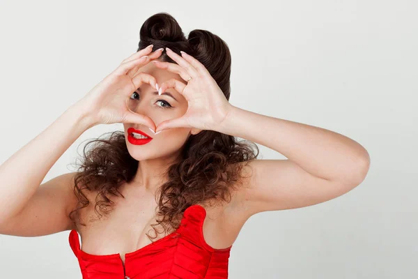 Charming lady in red corset, shows sign heart. Valentines day