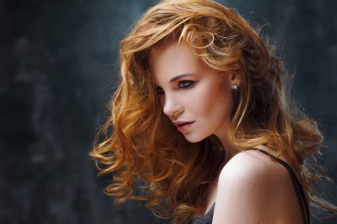 Mükemmel kıvırcık saçlı. Mutlu güzel kızıl saçlı kız. Stüdyo portre dokulu arka plan üzerinde.